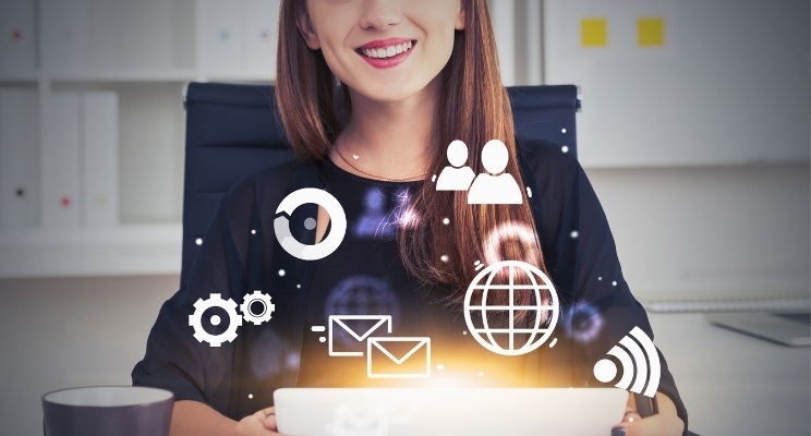 smiling businesswoman using tablet in office with blurry internet icons floating around