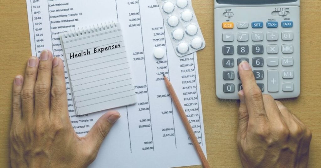 Man calculating health expenses with medication, calculator and notes on a table