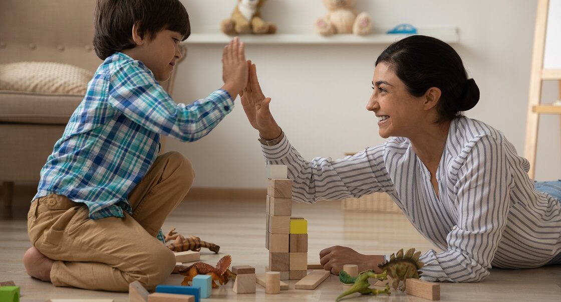 Laughing mom giving her son high five while playing with blocks