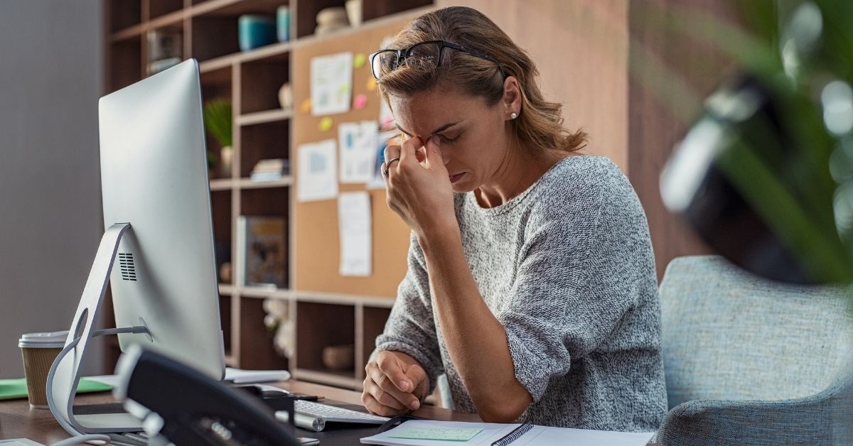 woman rubbing bridge of nose stressed at work with personal issues