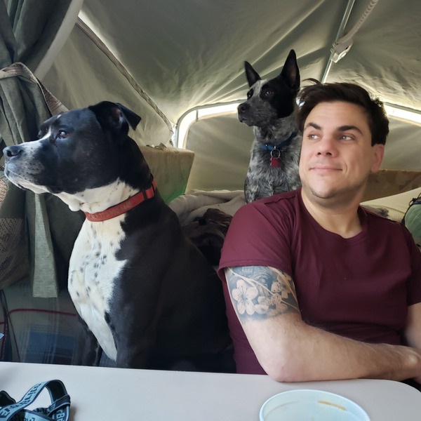 Fernando Orfila, VP of Product for RethinkBH camping in tent with two large dogs