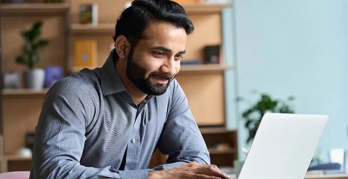 Man smiling while working on laptop