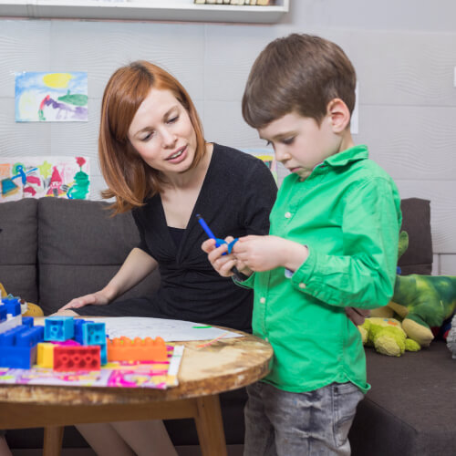 Female ABA working with child playing with blocks