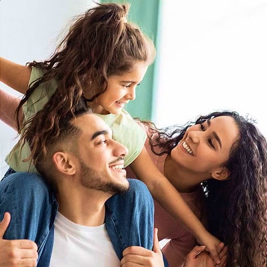 father with daughter on shoulders and mother smiling