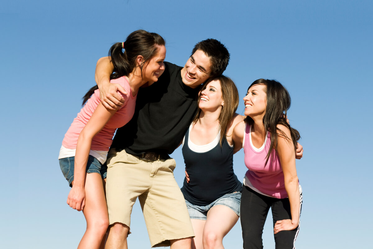 Group of happy young adults in huddle with blue sky background