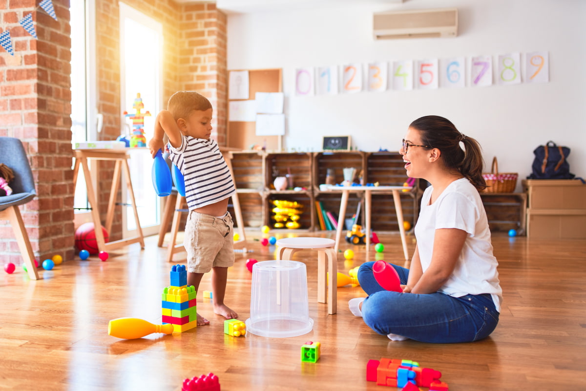 ABA provider in therapy session with toddler boy playing drum
