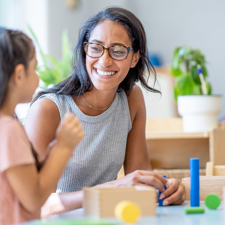 ABA provider with little girl patient stacking wooden blocks together