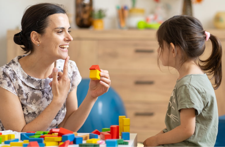 Adult speech therapy expert engages young child using colorful blocks